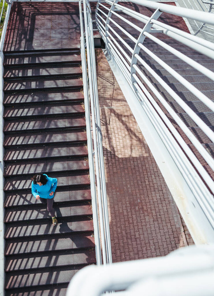 Eine Frau läuft die Treppe hinauf. Lauftraining in der Stadt. Joggen. Das Ziel erreicht. Der Wunsch nach dem Sieg. Training. - Foto, Bild