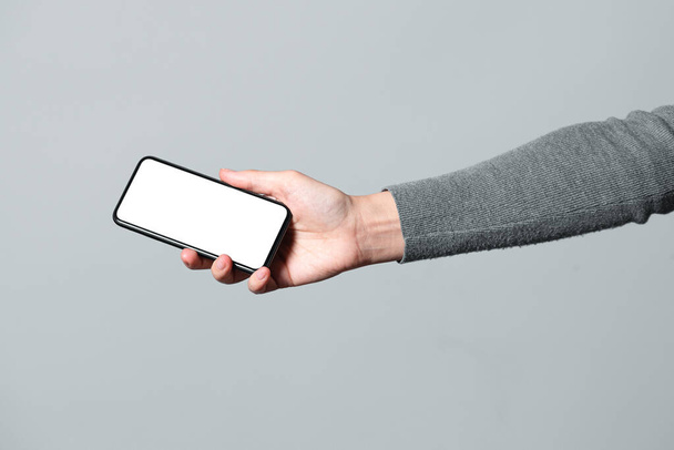 Mobile phone with copy space screen in female hand isolated on gray background. - Photo, Image