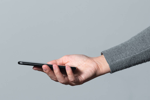 Мобільний телефон у жіночій руці ізольовано на сірому фоні
. - Фото, зображення