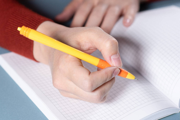Frau schreibt mit Kugelschreiber in ihr Notizbuch. - Foto, Bild