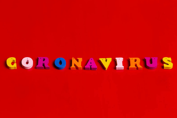 Pandemický a virový koncept - koronavirové slovo z barevných bloků. Text koronaviru na červeném pozadí. Coronavirus koncept top view. - Fotografie, Obrázek