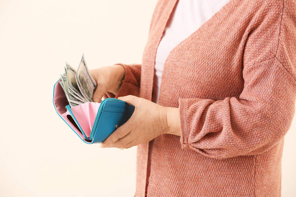 Senior woman with money on color background - Photo, Image