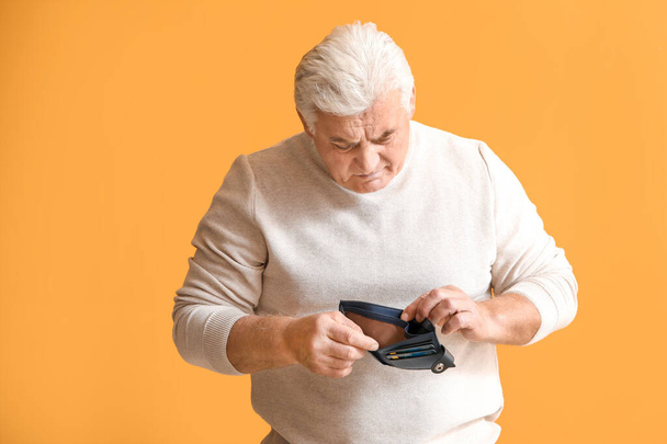 Sad senior man with empty purse on color background - Photo, Image