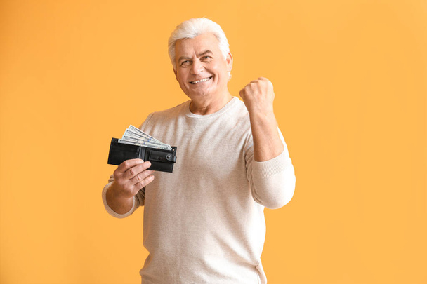 Happy senior man with purse on color background - Foto, afbeelding