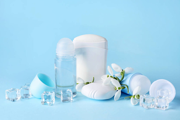 Different deodorants and flowers on color background - Photo, Image
