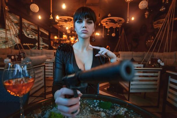 Portrait of a sexy young woman with a gun in her hands close up. - Photo, Image