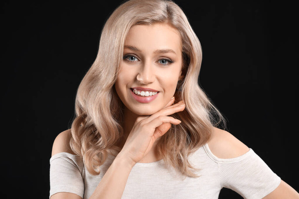 Young blonde with beautiful hair on dark background - 写真・画像