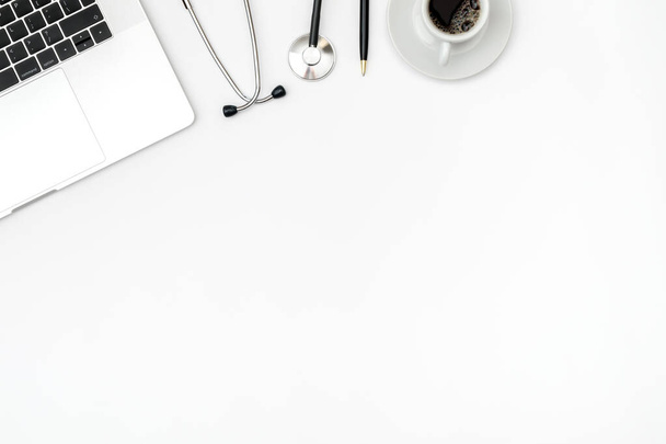 Luogo di lavoro di dottore moderno con computer portatile e stetoscopio su tavolo bianco. Vista dall'alto. Posa piatta - Foto, immagini