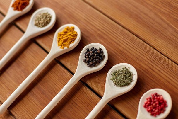 spoons with different spices on wooden table - Fotoğraf, Görsel