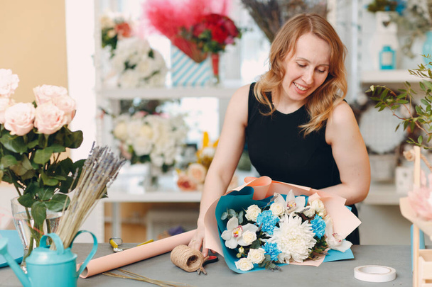 Florist makes a bouquet in a flower boutique - Foto, afbeelding