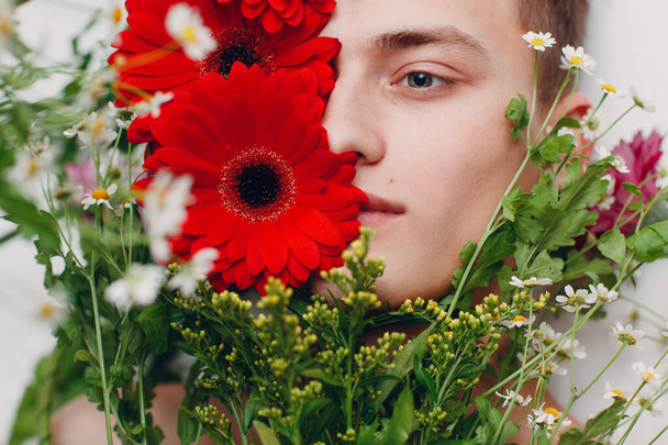 Young male model with flowers. Beauty portrait. - Φωτογραφία, εικόνα