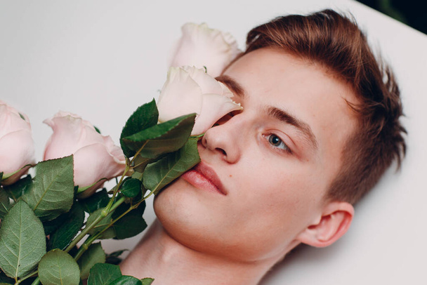 Fiatal férfi modell virágokkal. Szépségportré. - Fotó, kép