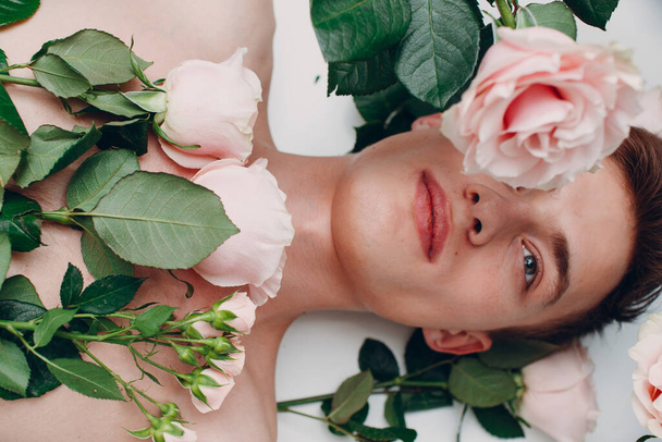 Modelo masculino jovem com flores. Retrato de beleza
. - Foto, Imagem