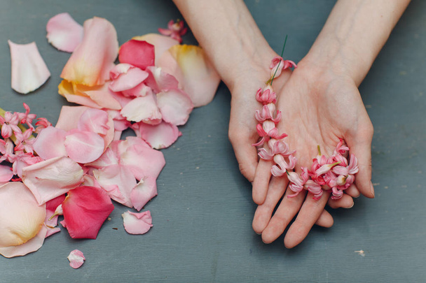 Ροζ πέταλα λουλουδιών στα χέρια της γυναίκας - Φωτογραφία, εικόνα
