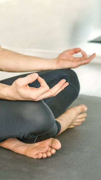 Yoga calm pose. Lotus asana studio training. Man seated at mat. Beginner class - 写真・画像