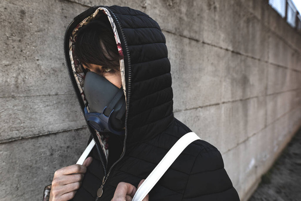 mulher com uma máscara de gás andando nas ruas da cidade sobrevivendo a uma pandemia do vírus da corona ou mundo pós-atômico
 - Foto, Imagem