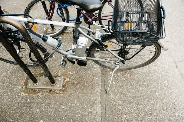 Вид зверху на сучасний електричний велосипед, припаркований біля сталевого паркану захисту в центральній частині міста
 - Фото, зображення