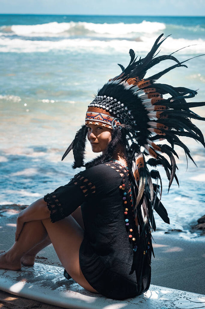 Deniz kenarında güneşli bir sahilde sörf tahtasında oturan yarı çıplak bir kadının yakın plan portresi, aztek kavramsal görünüş. - Fotoğraf, Görsel