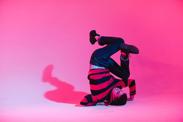 Young Man in a Jumper Dancing Contemporary Dance in Studio. Breakdancing. Dance School Poster. Copy Space. Battle competition announcement. Pink and Blue Background. - Fotografie, Obrázek