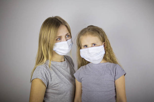 Mãe e pequena filha em máscaras médicas contra a infecção
 - Foto, Imagem