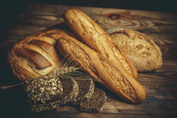 Різні хліби хліба, приготовані з борошном і безглютеновою пшеницею на дерев'яному столі
 - Фото, зображення