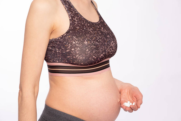 Pregnant woman holds a handful of vitamins; white background - Φωτογραφία, εικόνα