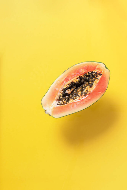 Halved papaya on yellow background. Top view. Copy space. Summer time. Tropical travel, exotic fruit. Vegan and vegetarian concept - Foto, imagen