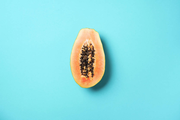 Halved papaya on blue background. Top view. Copy space. Summer time. Tropical travel, exotic fruit. Vegan and vegetarian concept - Foto, Bild
