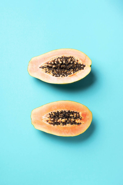 Halved papaya on blue background. Top view. Copy space. Summer time. Tropical travel, exotic fruit. Vegan and vegetarian concept - Fotoğraf, Görsel