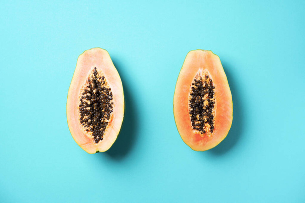 Halved papaya on blue background. Top view. Copy space. Summer time. Tropical travel, exotic fruit. Vegan and vegetarian concept - Foto, imagen