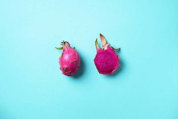 Pink pitahaya or dragon fruit on blue background. Top view. Copy space. Creative design banner. Summer time. Tropical travel, exotic fruit. Vegan and vegetarian concept - Zdjęcie, obraz