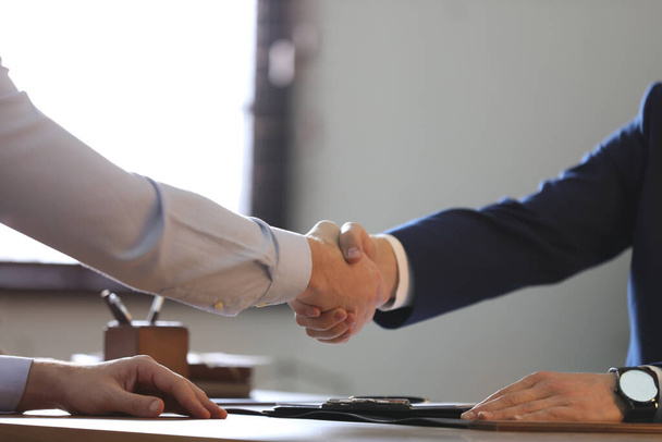 Male lawyer shaking hands with client in office, closeup - Foto, imagen