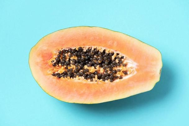 Halved papaya on blue background. Top view. Copy space. Summer time. Tropical travel, exotic fruit. Vegan and vegetarian concept - Foto, afbeelding