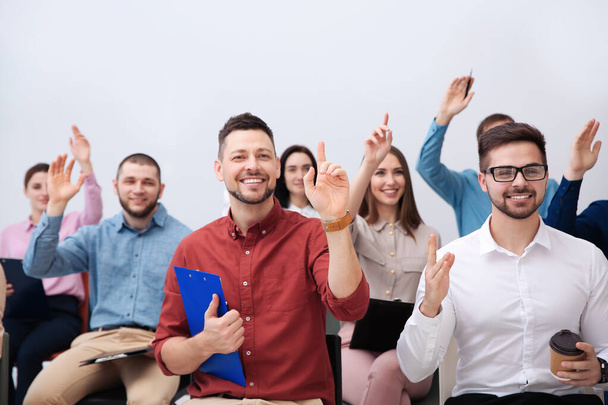Ihmiset, jotka nostavat kätensä esittämään kysymyksiä yrityskoulutuksessa valkoisella pohjalla
 - Valokuva, kuva