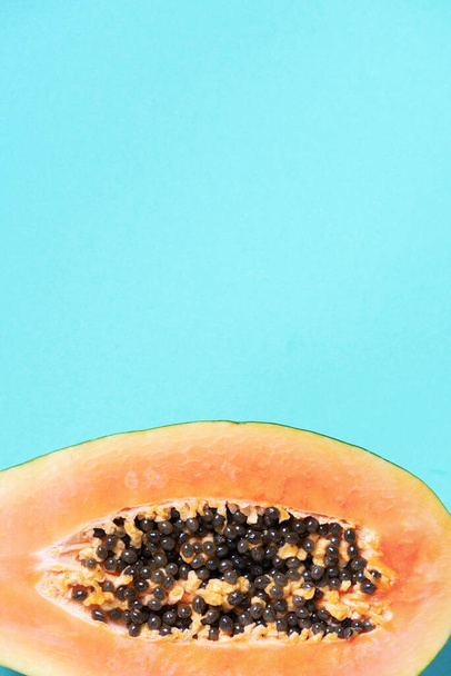 Halved papaya on blue background. Top view. Copy space. Summer time. Tropical travel, exotic fruit. Vegan and vegetarian concept - Foto, Bild