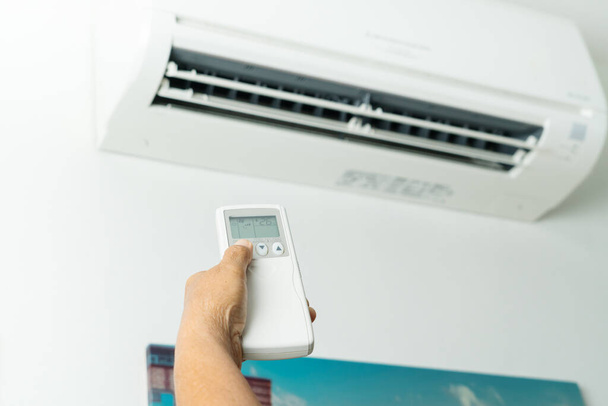 Controle remoto direcionado ao sistema de ar condicionado, controle de mão sênior ar condicionado em casa
 - Foto, Imagem