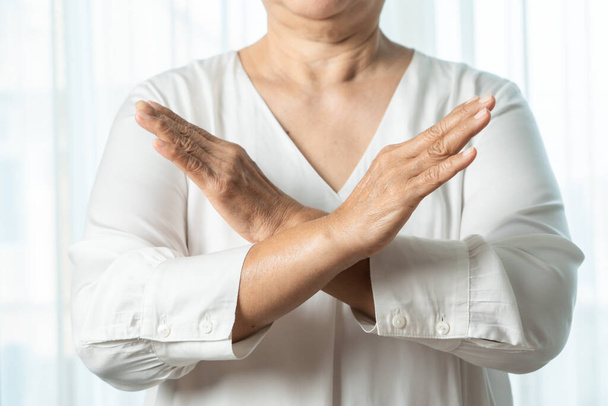 Senior asiático mujer decir no celebración de dos brazos cruzados
 - Foto, imagen