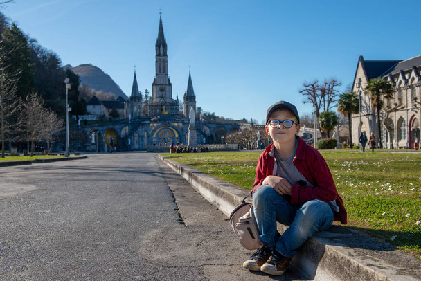 un joven con la basílica de Lourdes en Francia
 - Foto, Imagen