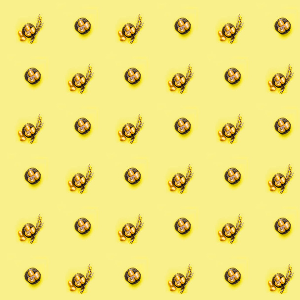Nest mit goldenen Ziereiern und Federn im Nest auf gelbem Hintergrund. Frühjahrsferienkonzept. Kopierraum, Vorlage-Attrappe Ostergrußkarte mit Platz für Text, nahtloser Hintergrund, Muster, Tapete - Foto, Bild