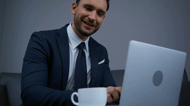 szelektív fókusz az üzletember gépelés laptop közelében csésze - Felvétel, videó