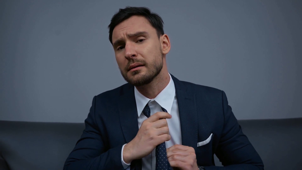 κουρασμένος επιχειρηματίας αγγίζοντας γραβάτα στο ξενοδοχείο  - Πλάνα, βίντεο
