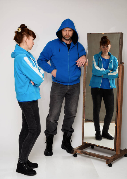 Full-length photo of man and woman in front of a mirror on a white background - Foto, Bild
