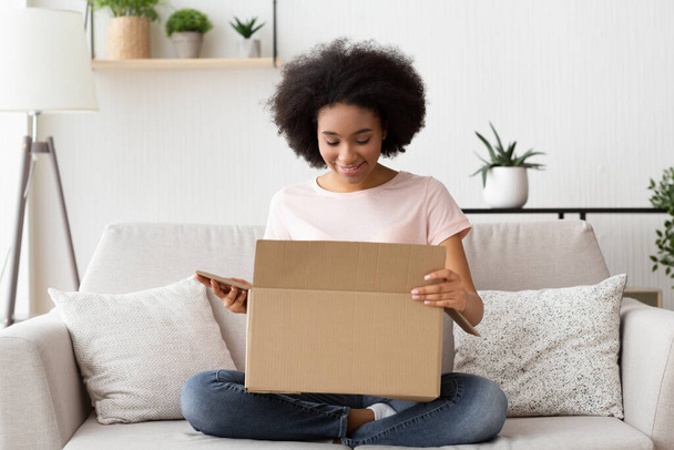 Girl with pleasure opens a box from online store - Photo, image