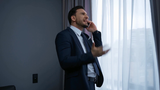 dissatisfied businessman talking on smartphone in hotel - Footage, Video