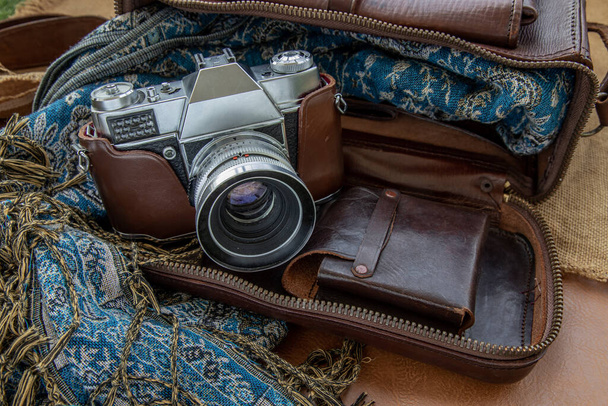 Un appareil photo vintage et un sac en cuir marron avec écharpe sur fond de sac en tissu. Conception de concept de voyage vacances. Ton de couleur vintage
. - Photo, image