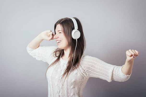 Young woman with headphones listening music .Music teenager girl dancing against isolated white background - Zdjęcie, obraz