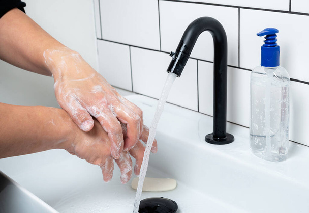 Handen wassen met zeep ter bescherming tegen bacteriën en virussen - Foto, afbeelding