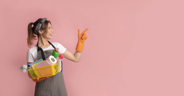 Cheerful Housewife Holding Basket With Cleaning Supplies And Pointing Aside - Photo, Image