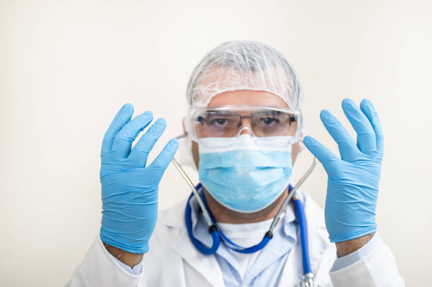 médico caucasiano com estetoscópio, equipamento de proteção e jaleco branco isolado sobre fundo branco
. - Foto, Imagem
