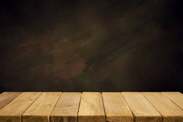 Enfoque seleccionado mesa de madera marrón vacía y textura de pared o imagen de fondo borrosa de pared de ladrillo negro viejo. para su fotomontaje o visualización del producto - Foto, imagen